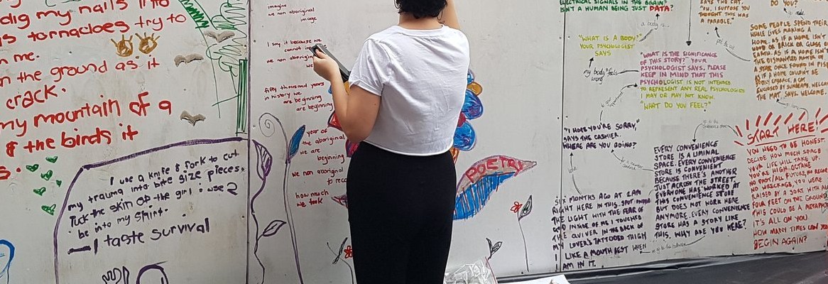 A person writing poetry on a pop-up wall.